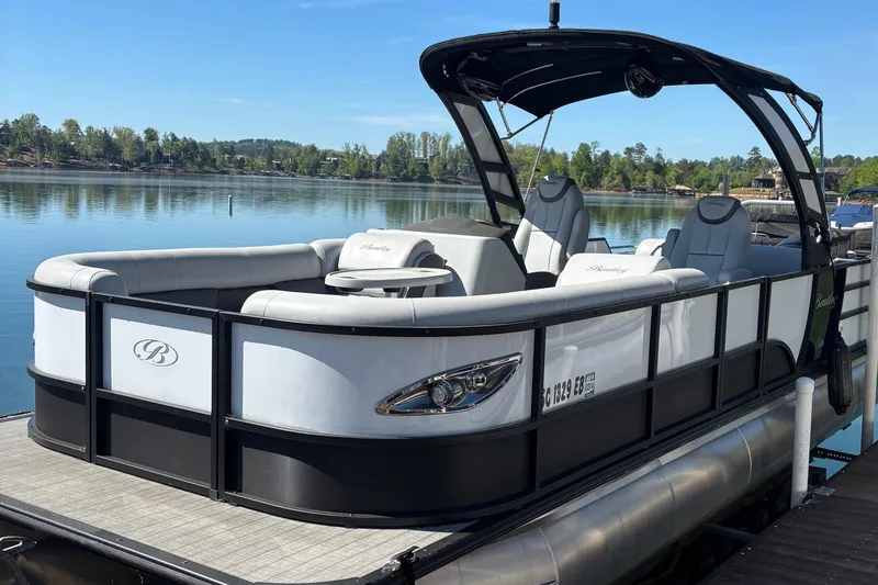 The Image of 2022 Bentley Pontoons Elite 253 Swingback on a serene lake, showcasing luxury seating and sleek design. - 0