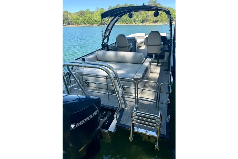 Slide: The Image of 2022 Bentley Pontoons Elite 253 Swingback on a serene lake with lush greenery. - 2