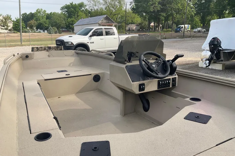 Slide: The Image of 2026 Excel 1751 River Warrior SC boat interior with steering console, parked near a white truck. - 4
