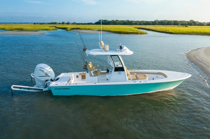 Slide: The Image of Manufacturer Provided Image: 2025 Sportsman Masters 267OE Bay Boat on calm water, featuring fishing rods and outboard motor. - 2