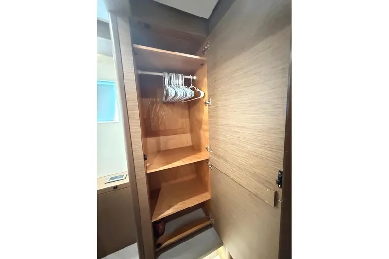Slide: The Image of Open wooden closet with shelves and hangers inside a 2021 Lagoon 50 yacht. - 25