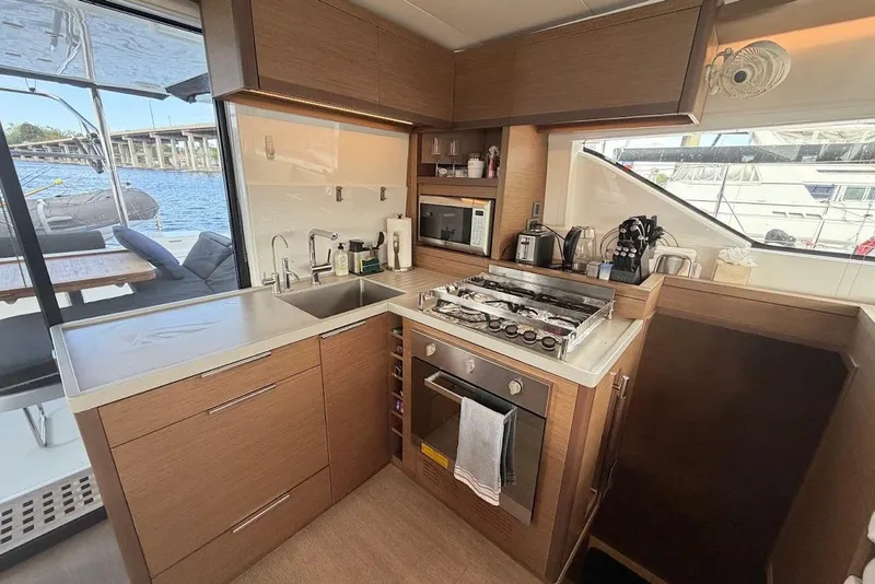 Slide: The Image of Modern kitchen interior on a 2021 Lagoon 50 yacht, featuring sleek appliances and wooden cabinetry. - 8