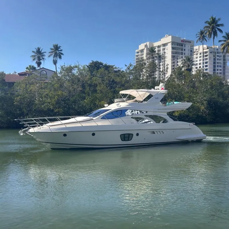 The Image of 2007 Azimut 55E yacht cruising on a calm river with lush greenery. - 0