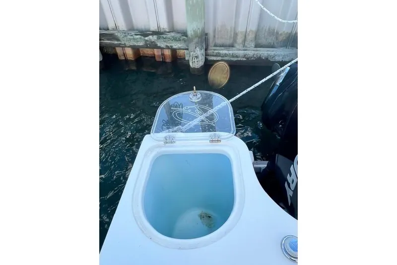 Slide: The Image of Open livewell on 2014 Sailfish 270 CC boat docked by wooden pier. - 11