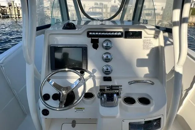 Slide: The Image of 2014 Sailfish 270 CC boat dashboard with steering wheel, gauges, and controls. - 2