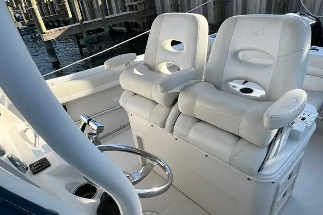 Slide: The Image of 2014 Sailfish 270 CC boat interior with dual white captain's chairs and steering wheel. - 6