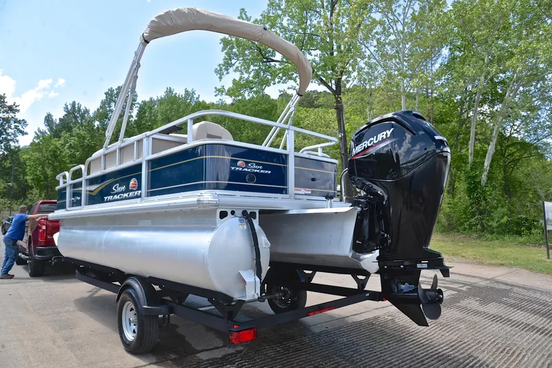 Slide: The Image of 2024 Sun Tracker Bass Buggy 18 DLX pontoon boat on trailer, featuring Mercury outboard motor. - 12
