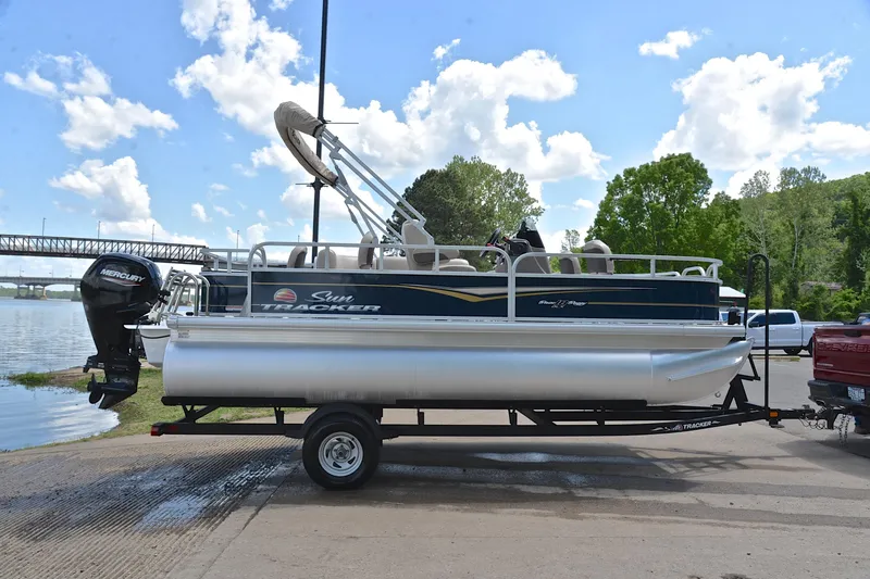 Slide: The Image of 2024 Sun Tracker Bass Buggy 18 DLX pontoon boat on trailer by a lake. - 15
