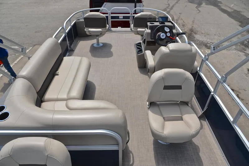Slide: The Image of 2024 Sun Tracker Bass Buggy 18 DLX pontoon boat interior with beige seating and steering console. - 18