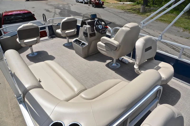 Slide: The Image of 2024 Sun Tracker Bass Buggy 18 DLX pontoon boat interior with beige seating and steering console. - 24