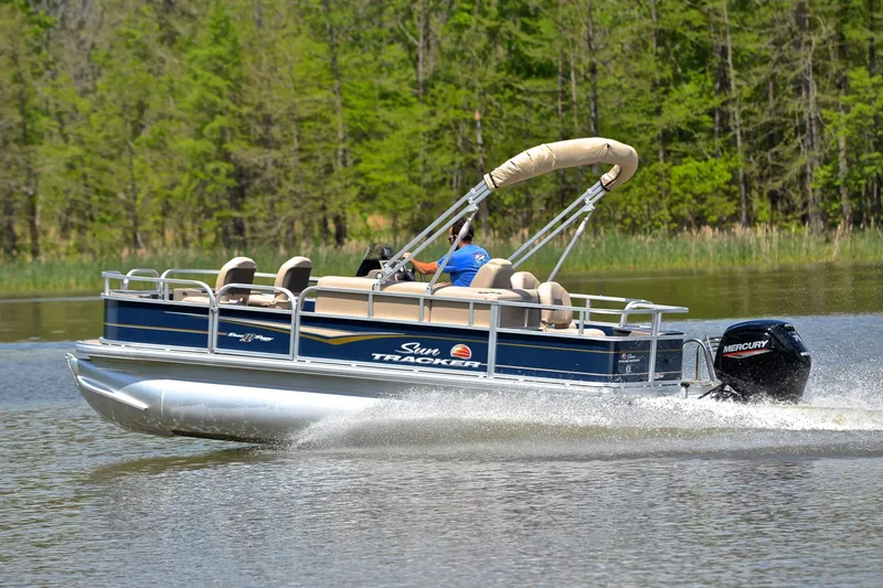 Slide: The Image of 2024 Sun Tracker Bass Buggy 18 DLX pontoon boat cruising on a lake. - 4