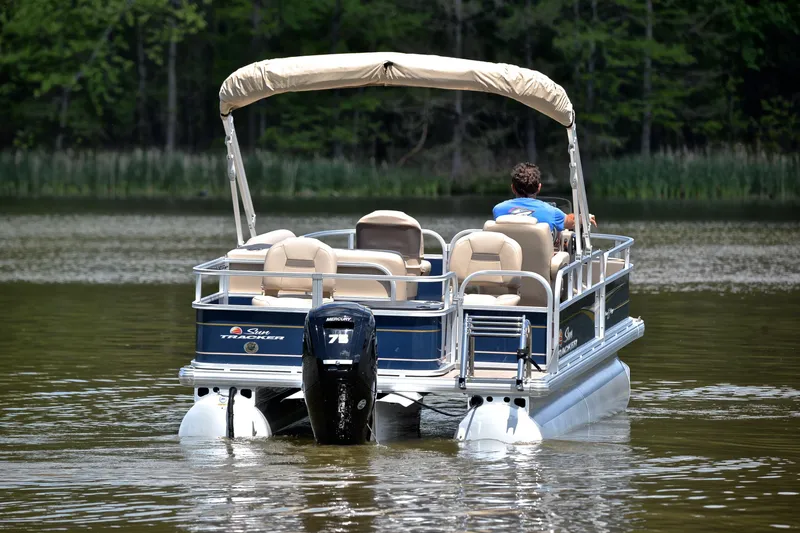 Slide: The Image of 2024 Sun Tracker Bass Buggy 18 DLX pontoon boat on a calm lake. - 7