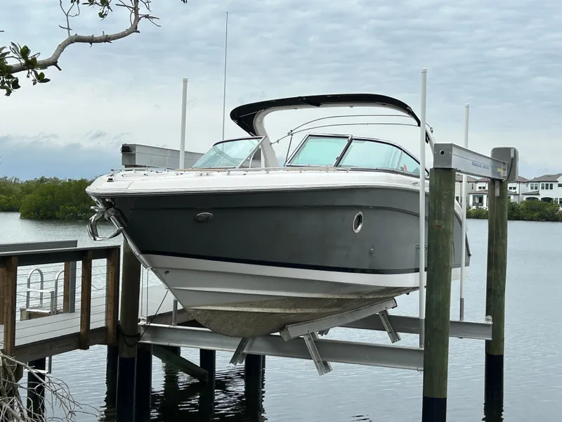 The Image of 2013 Regal 3200 Bowrider boat on lift by waterfront, overcast sky. - 10