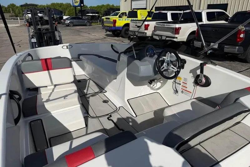 Slide: The Image of 2020 Tahoe T16 boat interior with seating and steering wheel, parked outdoors. - 9