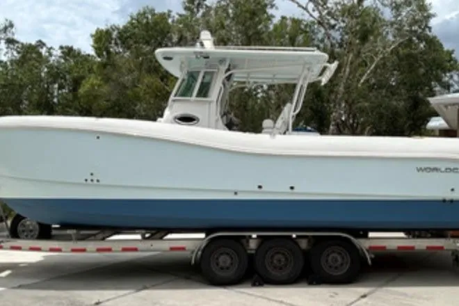 The Image of 2018 World Cat 320 CC boat on trailer, side view with trees in background. - 0