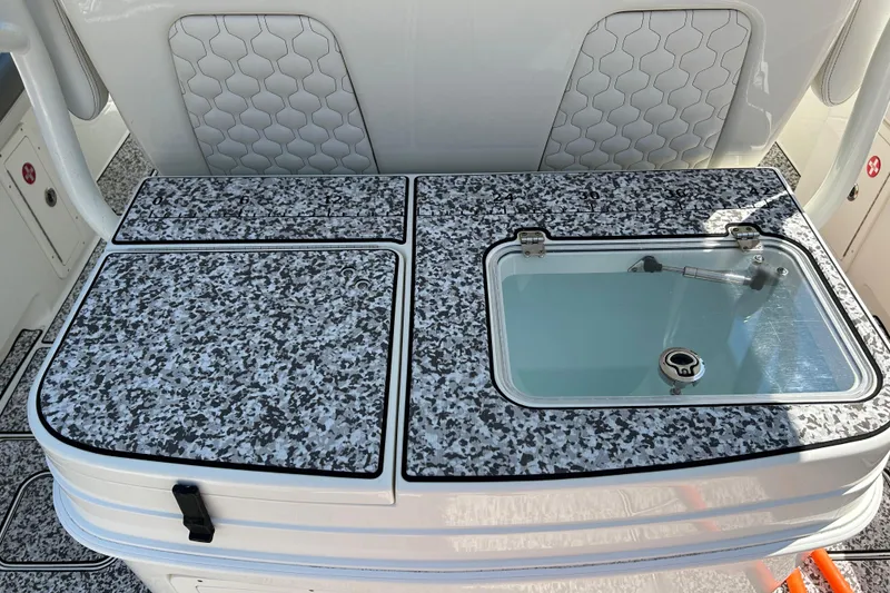 Slide: The Image of 2018 World Cat 320 CC boat interior with speckled countertop and built-in storage. - 17