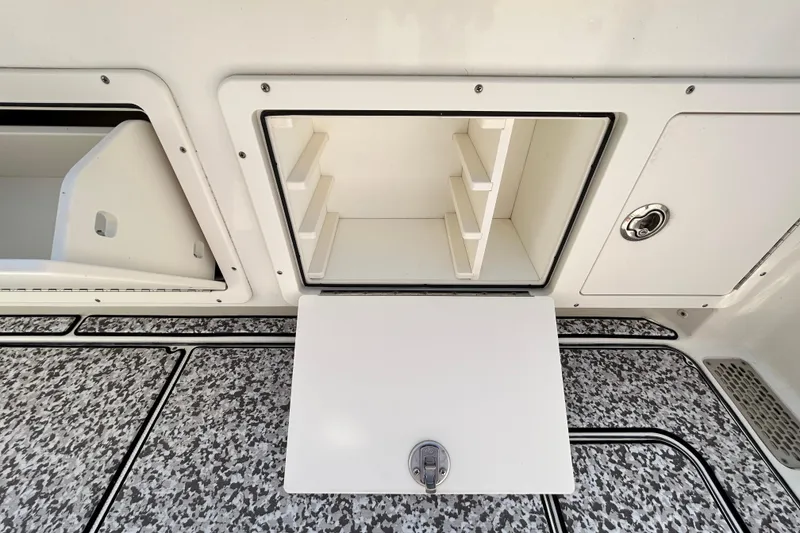 Slide: The Image of 2018 World Cat 320 CC boat storage compartment with open hatch and shelving. - 21