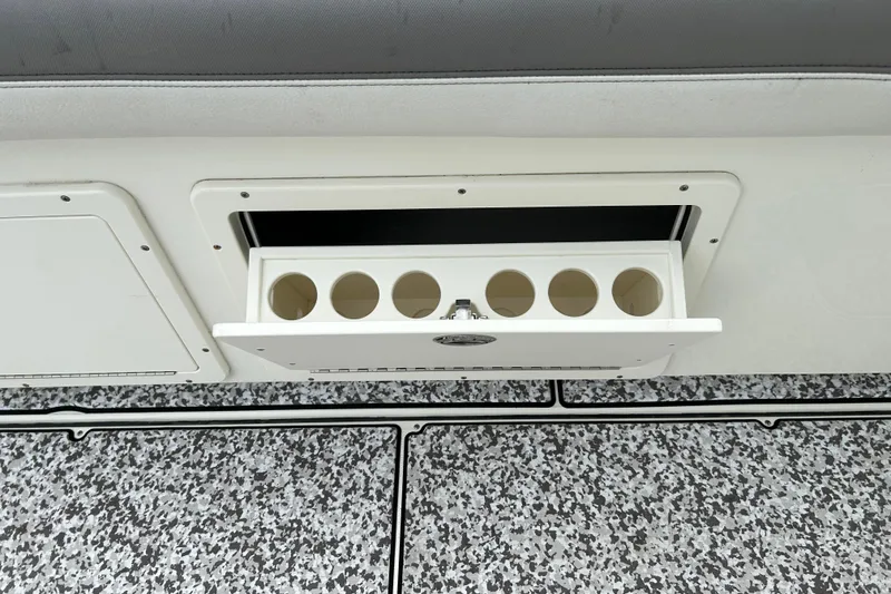 Slide: The Image of 2018 World Cat 320 CC boat storage compartment with cup holders on speckled deck. - 29