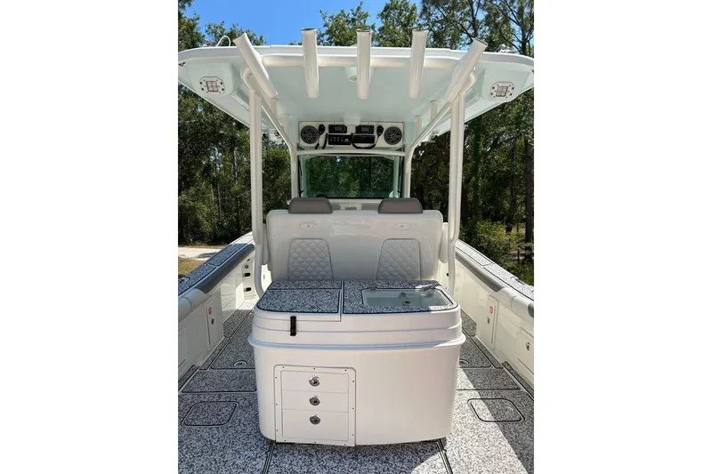 Slide: The Image of 2018 World Cat 320 CC boat interior with seating and storage, surrounded by trees. - 8