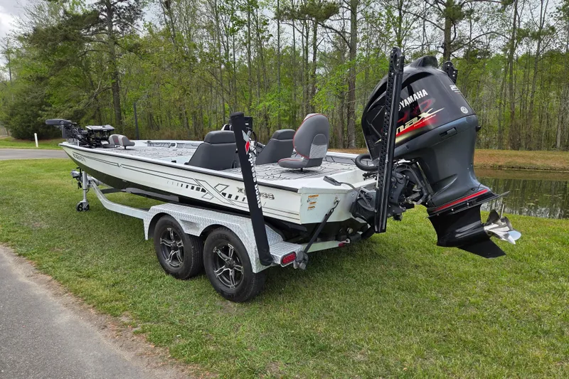 Slide: The Image of 2021 Xpress X21 Pro boat with Yamaha engine on grassy area near water. - 2