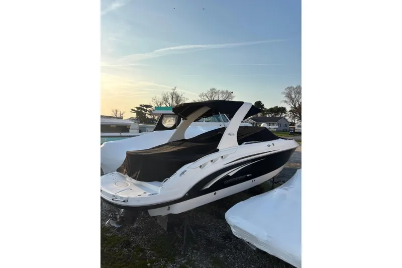 The Image of 2012 Chaparral 267 SSX boat with cover, parked outdoors at sunset. - 0