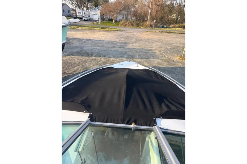 Slide: The Image of 2012 Chaparral 267 SSX boat with black cover, parked on a gravel lot. - 9