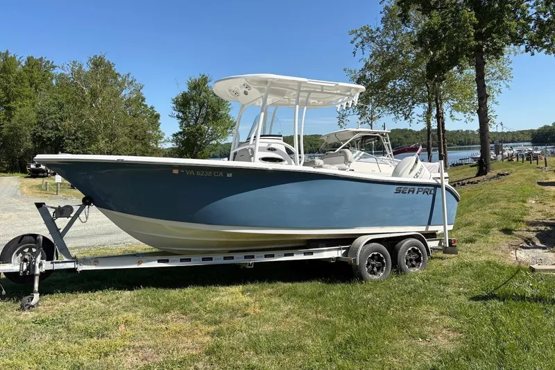 The Image of 2018 Sea Pro 219 Center Console boat on trailer, parked on grassy area near trees. - 0