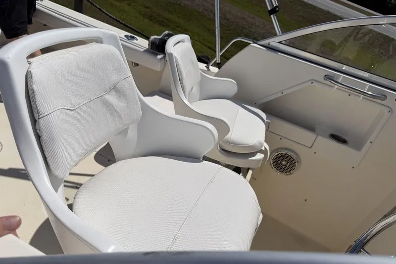 Slide: The Image of 2003 Sea Hunt Victory 215 boat interior with white cushioned seats and steering area. - 2