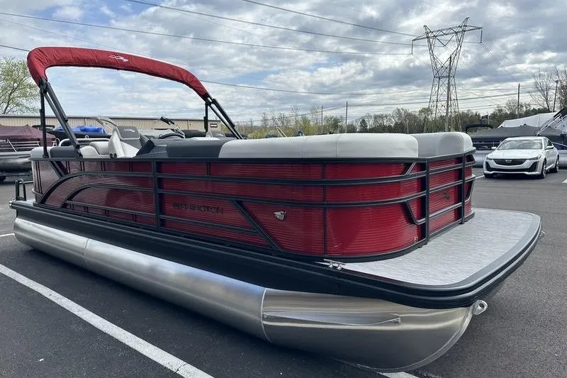 Slide: The Image of 2026 Bennington S Swingback 22 SSB pontoon boat with red and black design in parking lot. - 12