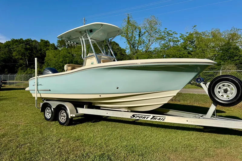 The Image of 2019 Pioneer 222 Sportfish boat on trailer, parked on grass with trees in background. - 1