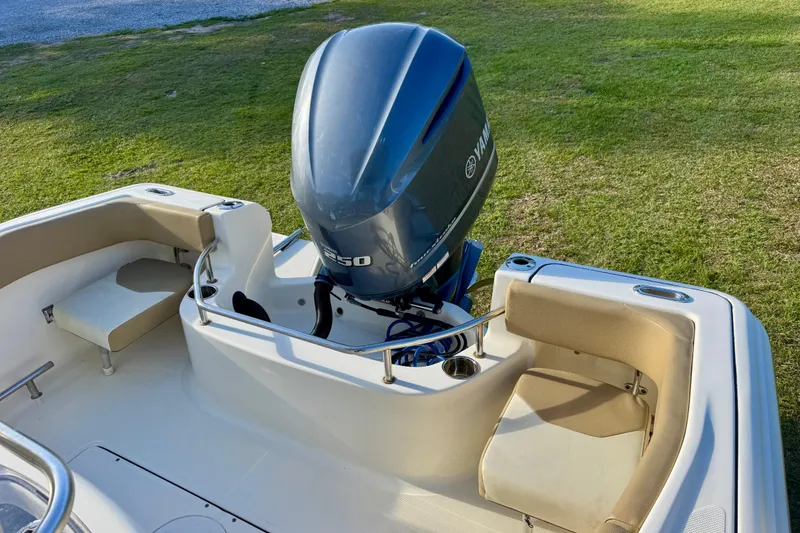 Slide: The Image of 2019 Pioneer 222 Sportfish boat with Yamaha engine, beige seating, and grassy background. - 10