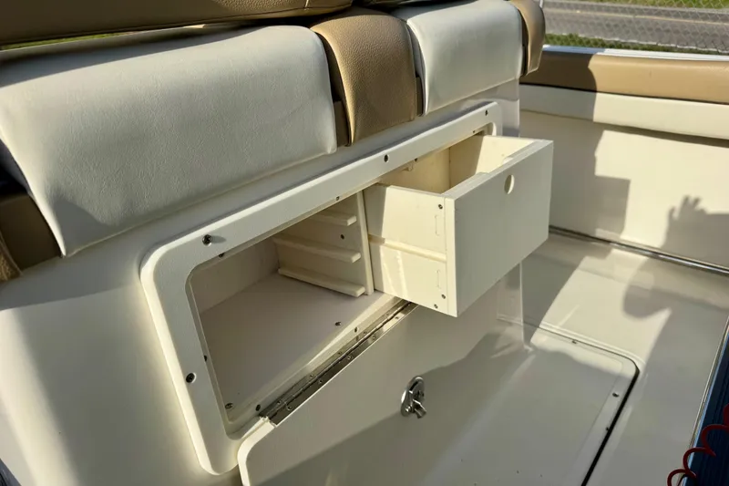 Slide: The Image of 2019 Pioneer 222 Sportfish boat interior with open storage compartment and cushioned seating. - 16