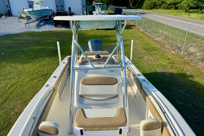 Slide: The Image of 2019 Pioneer 222 Sportfish boat with T-top, parked on grass near a fence. - 7