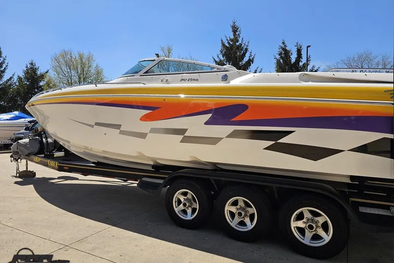 Slide: The Image of 2001 Powerquest 340 Vyper boat with vibrant graphics on a trailer, parked outdoors. - 21