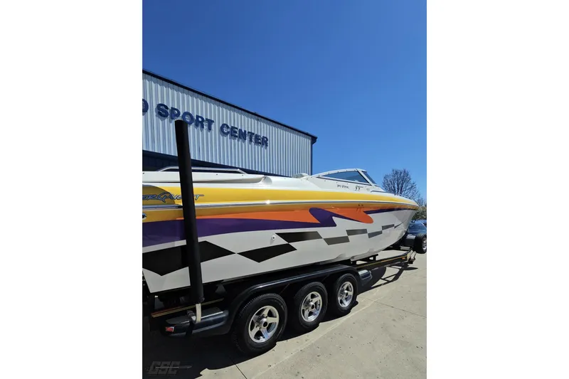Slide: The Image of 2001 Powerquest 340 Vyper boat with vibrant graphics on a trailer outside a sport center. - 27
