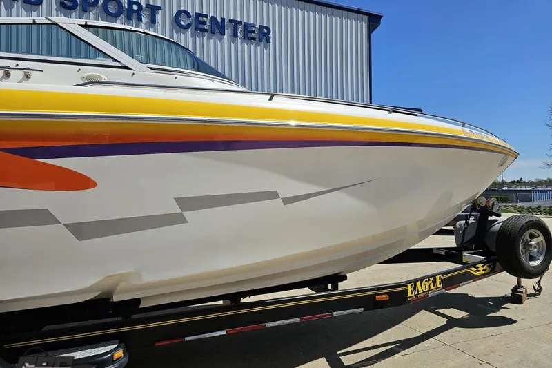 Slide: The Image of 2001 Powerquest 340 Vyper boat on trailer, vibrant graphics, parked near sport center. - 5
