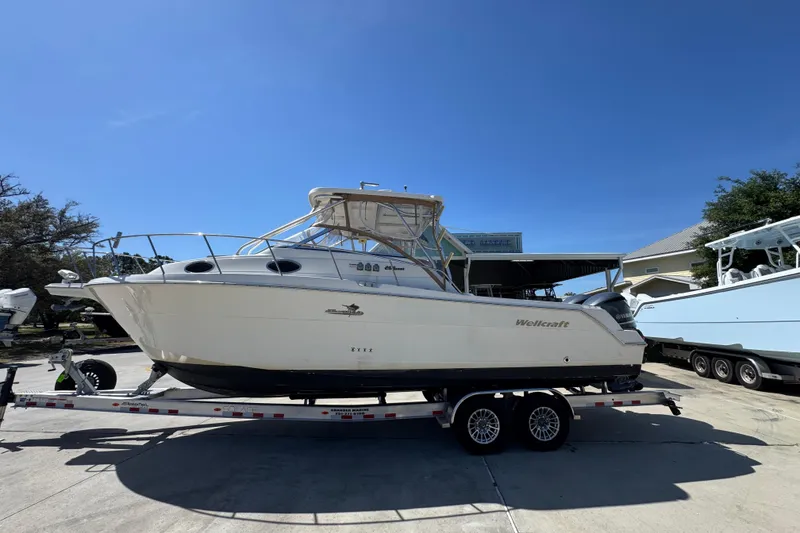 The Image of 2004 Wellcraft 290 Coastal boat on trailer under clear blue sky. - 1
