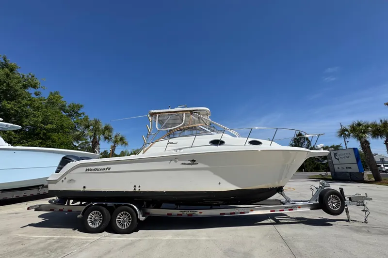 Slide: The Image of 2004 Wellcraft 290 Coastal boat on trailer under clear blue sky. - 10