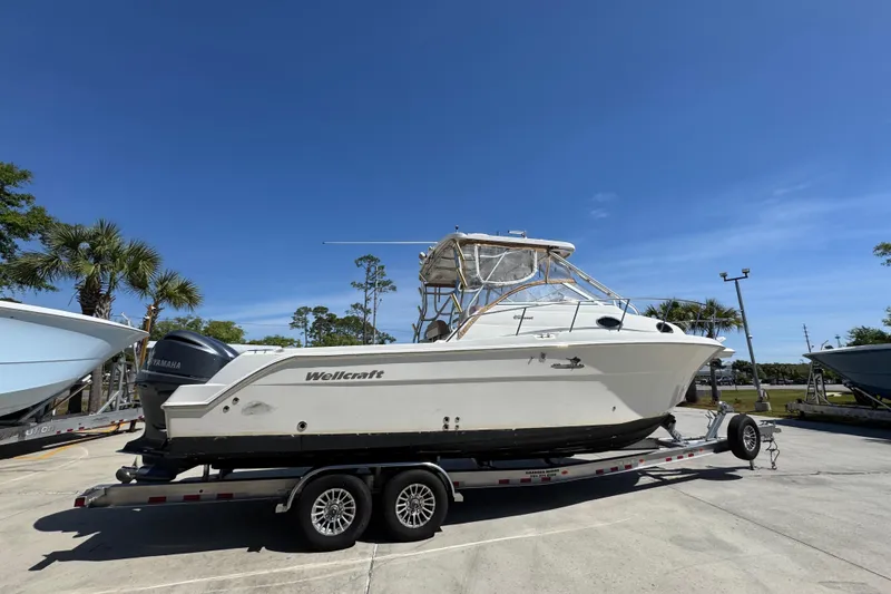 Slide: The Image of 2004 Wellcraft 290 Coastal boat on trailer under clear blue sky. - 11