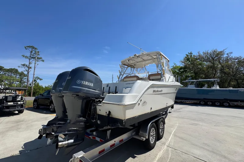 Slide: The Image of 2004 Wellcraft 290 Coastal boat on trailer with Yamaha engines, parked outdoors. - 13