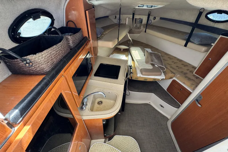 Slide: The Image of Interior of a 2004 Wellcraft 290 Coastal boat, featuring a compact kitchen and cozy sleeping area. - 26