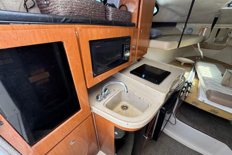 Slide: The Image of 2004 Wellcraft 290 Coastal cabin interior with kitchenette, sink, and sleeping area. - 27