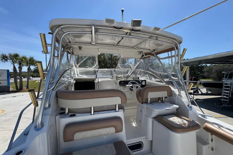 Slide: The Image of 2004 Wellcraft 290 Coastal boat interior with seating and helm, under clear blue sky. - 33
