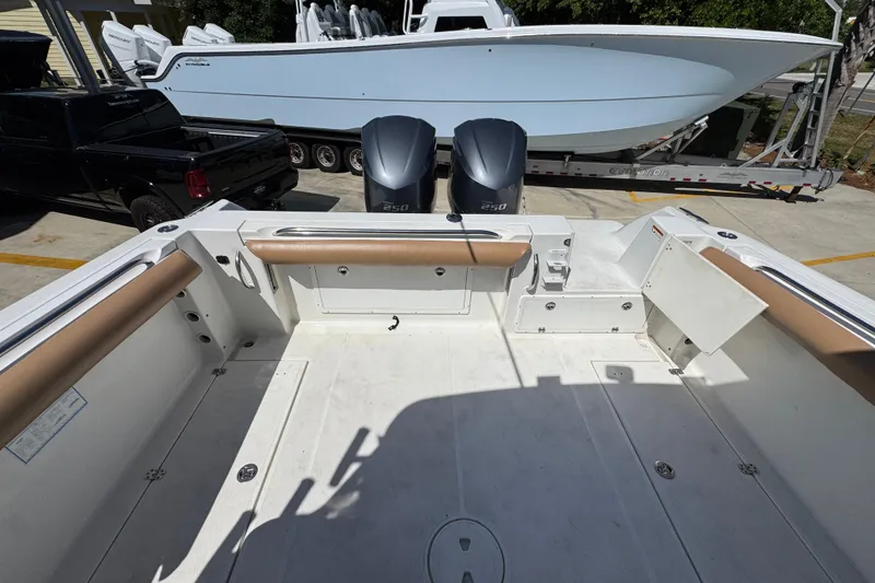 Slide: The Image of 2004 Wellcraft 290 Coastal boat deck with twin 250 engines, parked near a trailer. - 34