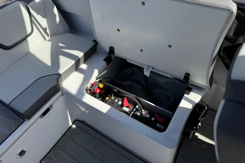 Slide: The Image of 2024 Yamaha Boats 252XE interior storage compartment with open lid, revealing battery and wiring. - 29
