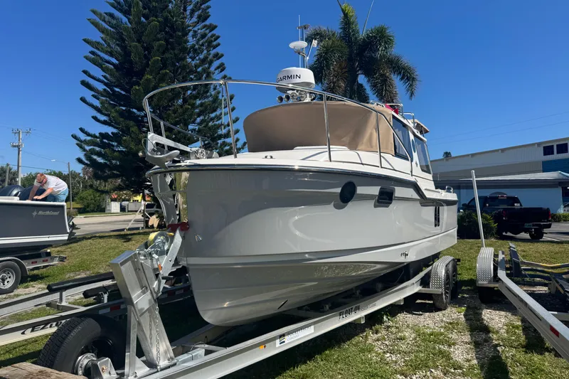 The Image of 2026 Ranger Tugs R-25 boat on trailer, parked outdoors under clear blue sky. - 1