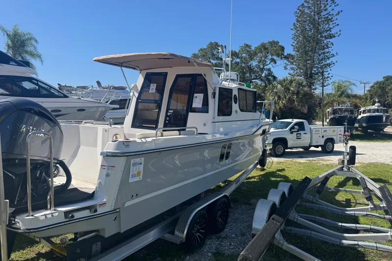 Slide: The Image of 2026 Ranger Tugs R-25 boat on trailer, parked outdoors under clear blue sky. - 3