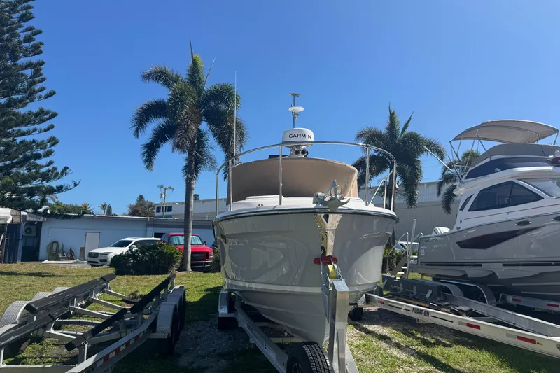 Slide: The Image of 2026 Ranger Tugs R-25 boat on trailer, surrounded by palm trees and other boats. - 4
