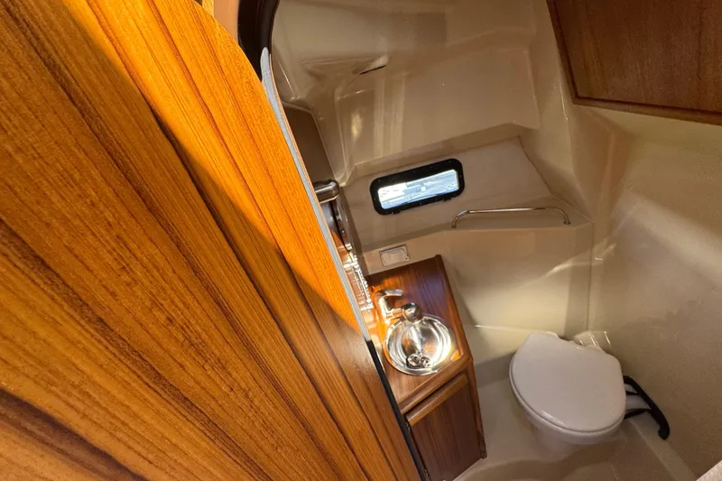 Slide: The Image of 2026 Ranger Tugs R-25 boat interior bathroom with wooden cabinetry and compact design. - 5