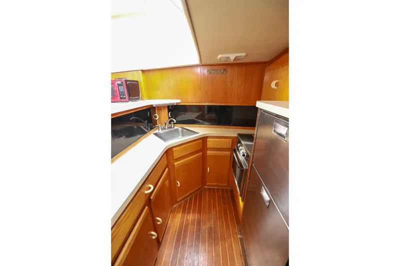 Slide: The Image of 1991 Silverton 41 Aft Cabin kitchen with wood cabinetry, stainless appliances, and red microwave. - 16
